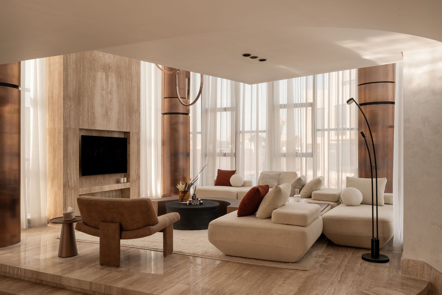 Modern luxury living room with travertine walls, cream sectional sofa, wooden coffee table, and floor-to-ceiling sheer curtains.