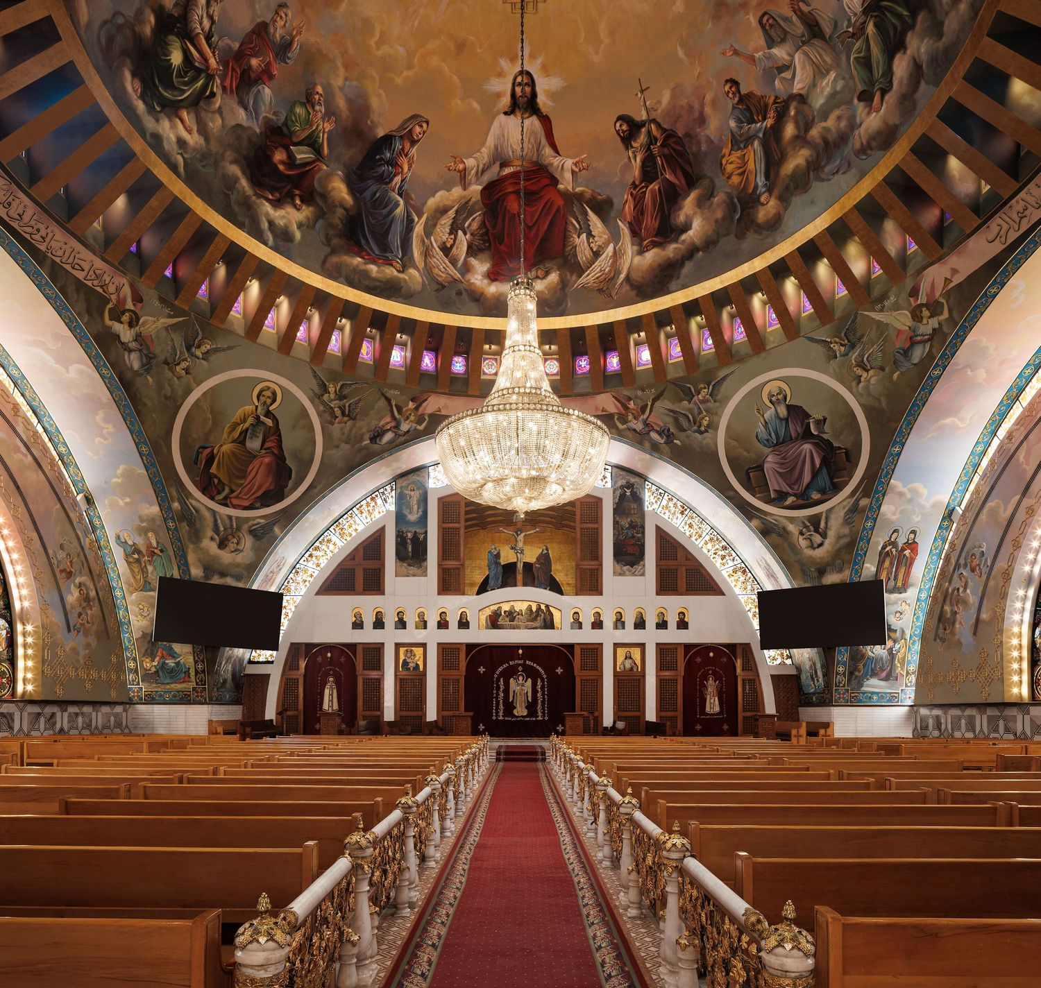 Ornate church interior with red carpet aisle and painted religious murals on domed ceiling. Interior Photography