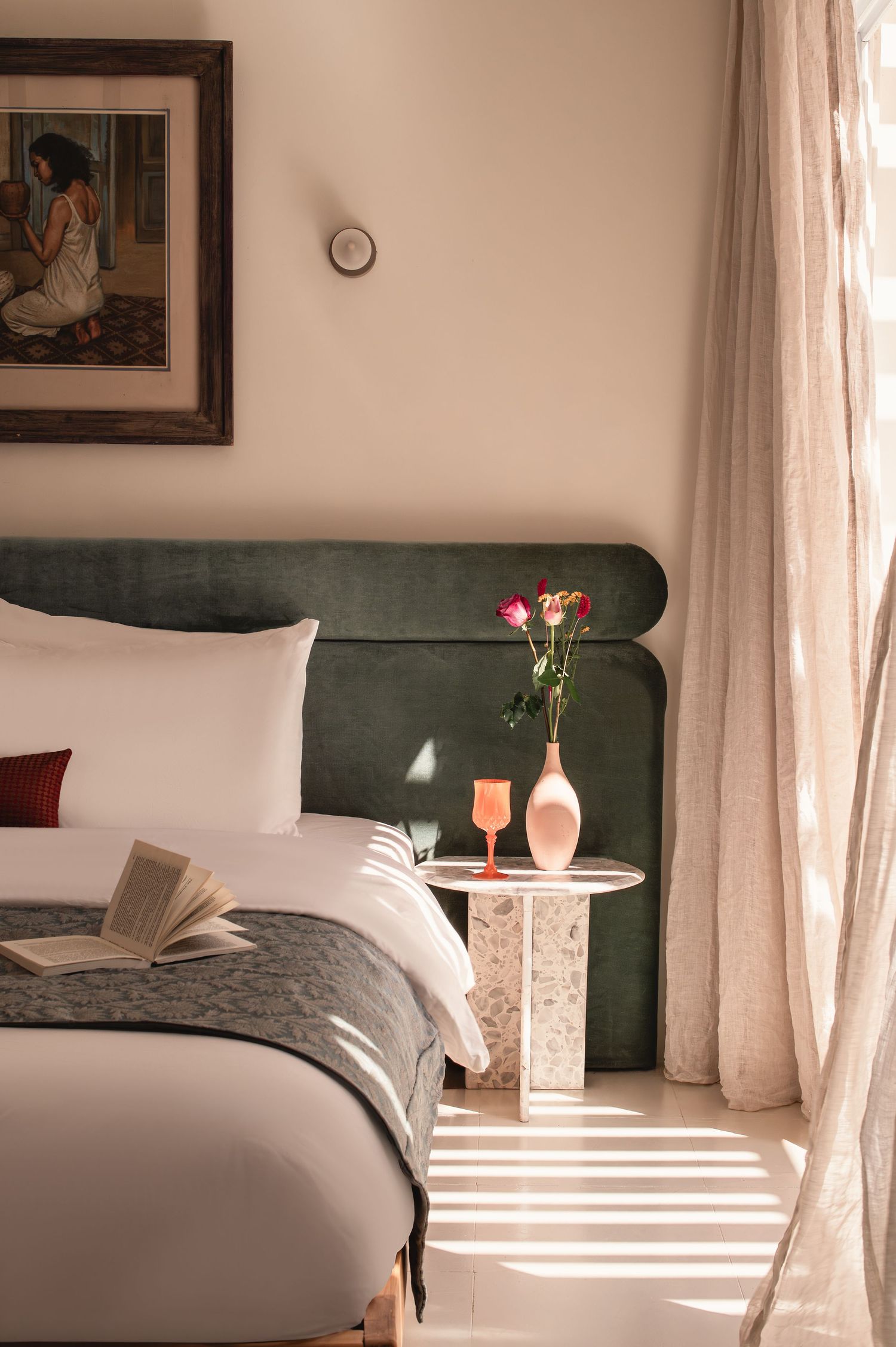 Elegant bedroom with green velvet headboard, white bedding, and sunlit window. Interior Photography