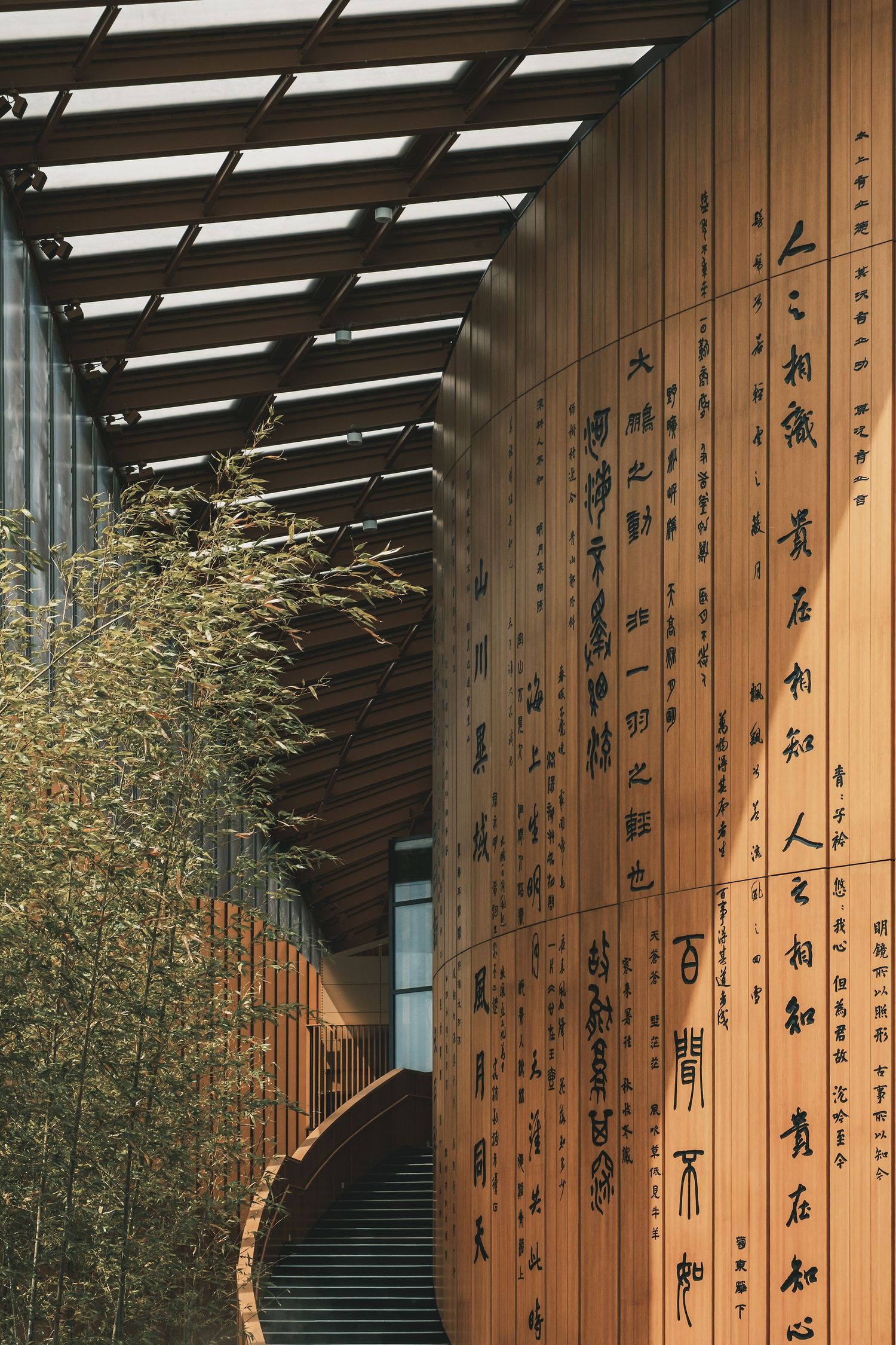 Contemporary hallway with wooden panels featuring vertical Chinese calligraphy and bamboo plants. Interior Photography