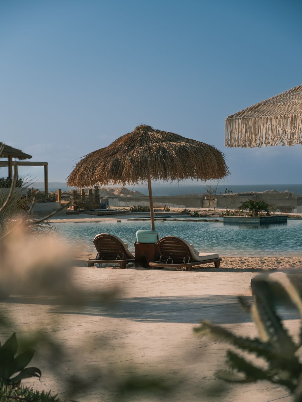 Luxury beach resort with thatched palapas and lounge chairs overlooking calm ocean waters. Interior Photography