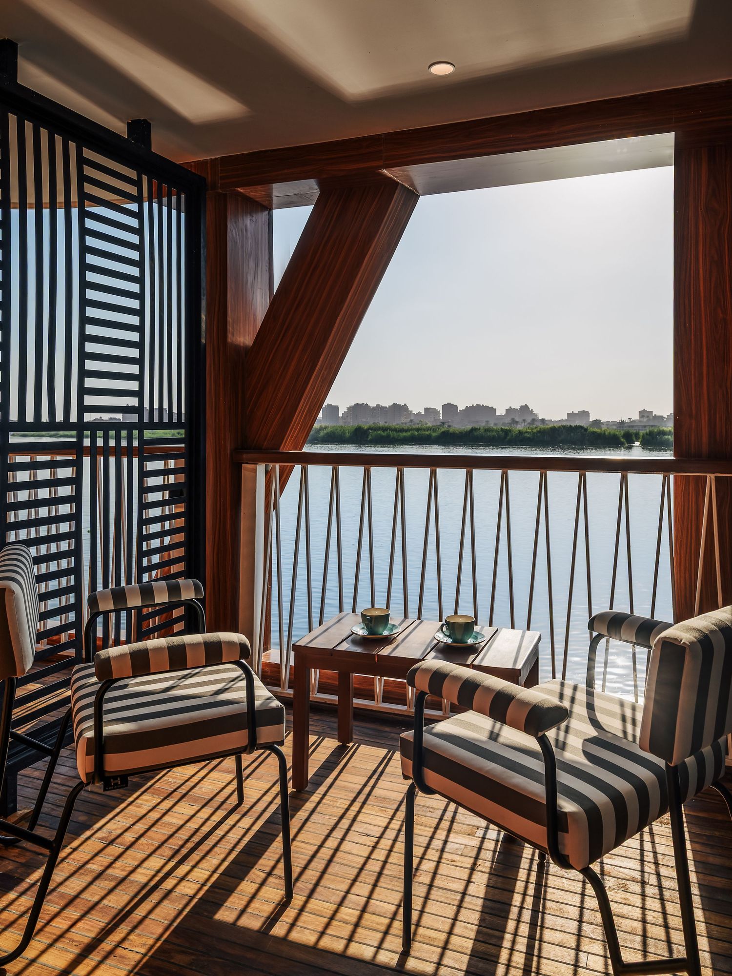 Modern balcony lounge with striped furniture overlooking waterfront views. Interior Photography