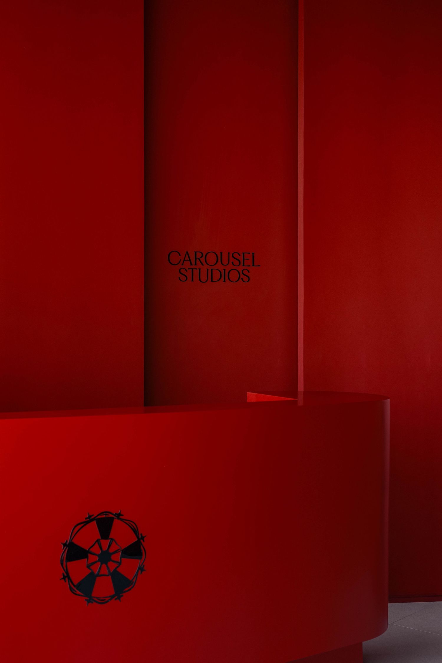 Red interior wall with Carousel Studios branding and geometric logo design. Interior Photography