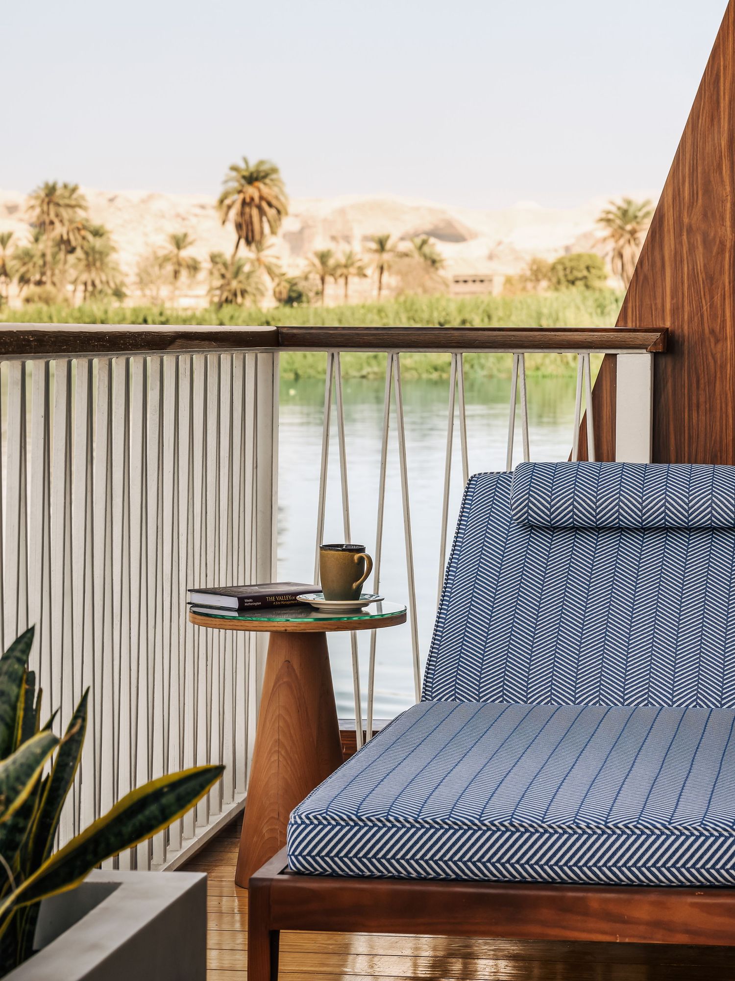 Waterfront seating area with striped cushions and palm trees in background. Interior Photography