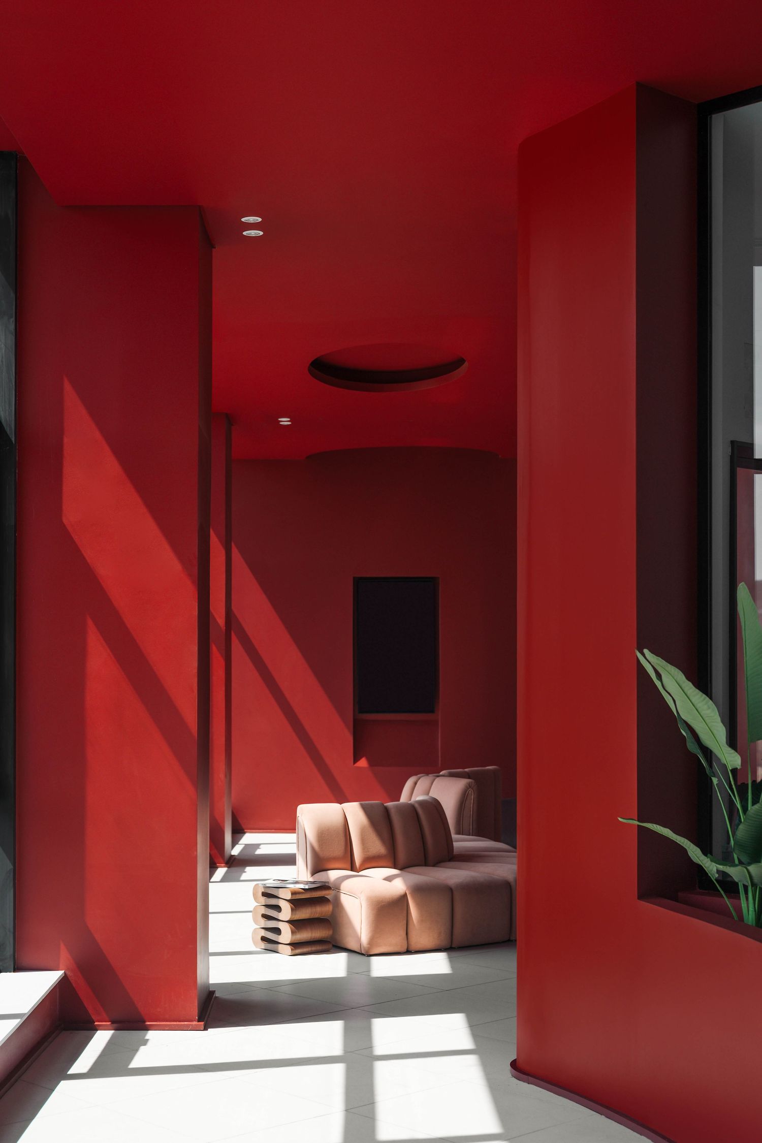 Minimalist interior with bold red walls and dramatic shadows from natural lighting. Interior Photography