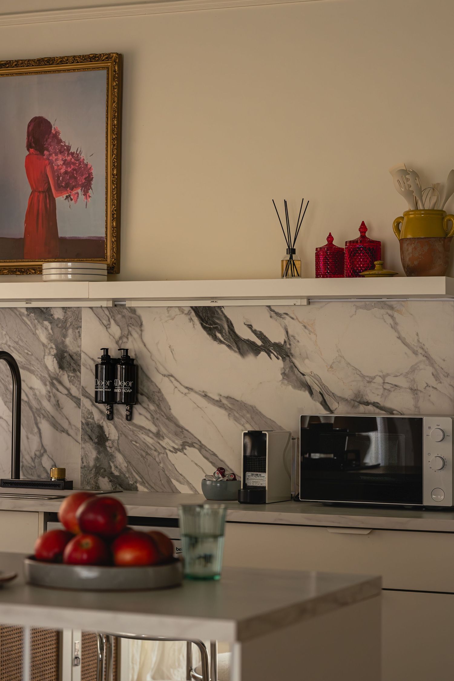 Kitchen with marble backsplash, built-in appliances, and red fruit bowl on counter. Interior Photography