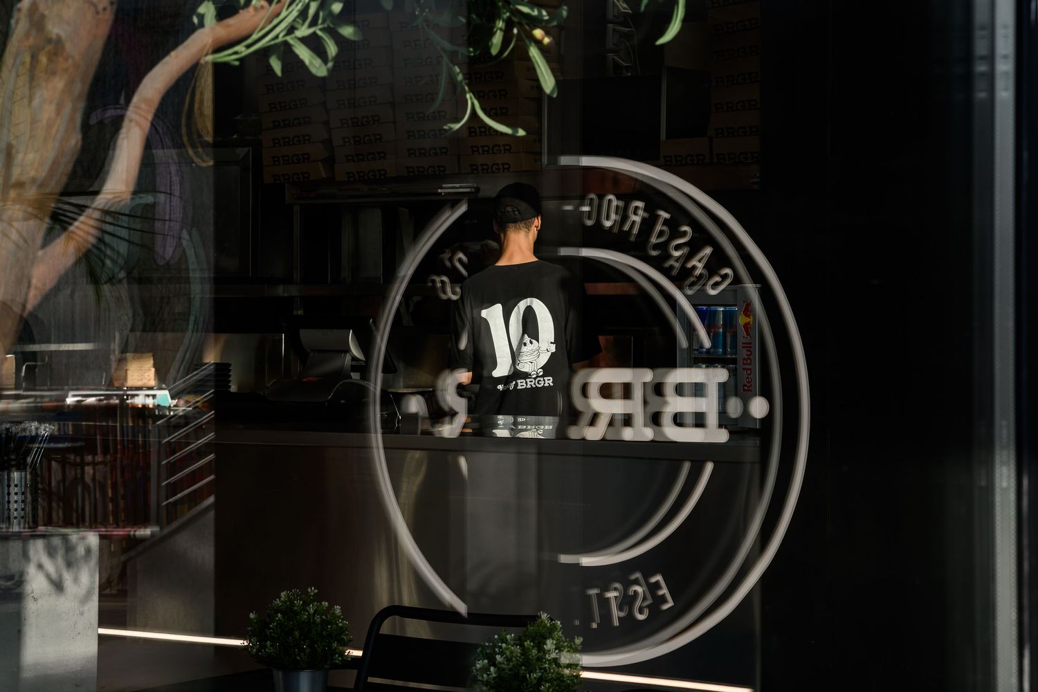 Modern coffee shop interior with dark ambiance and illuminated signage on wall. Interior Photography