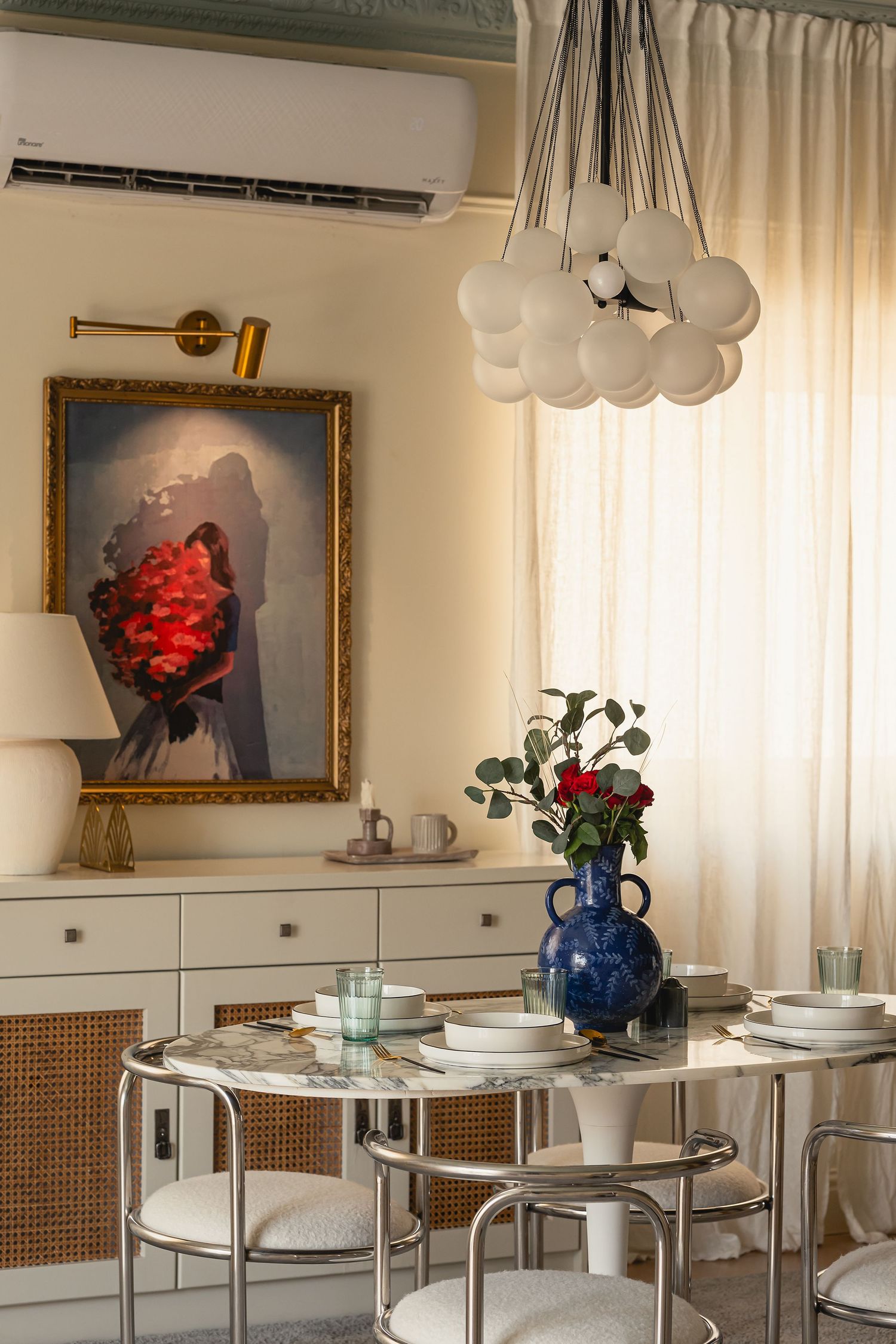 Elegant dining area with glass tables, white chairs, and artwork displayed on cream walls. Interior Photography