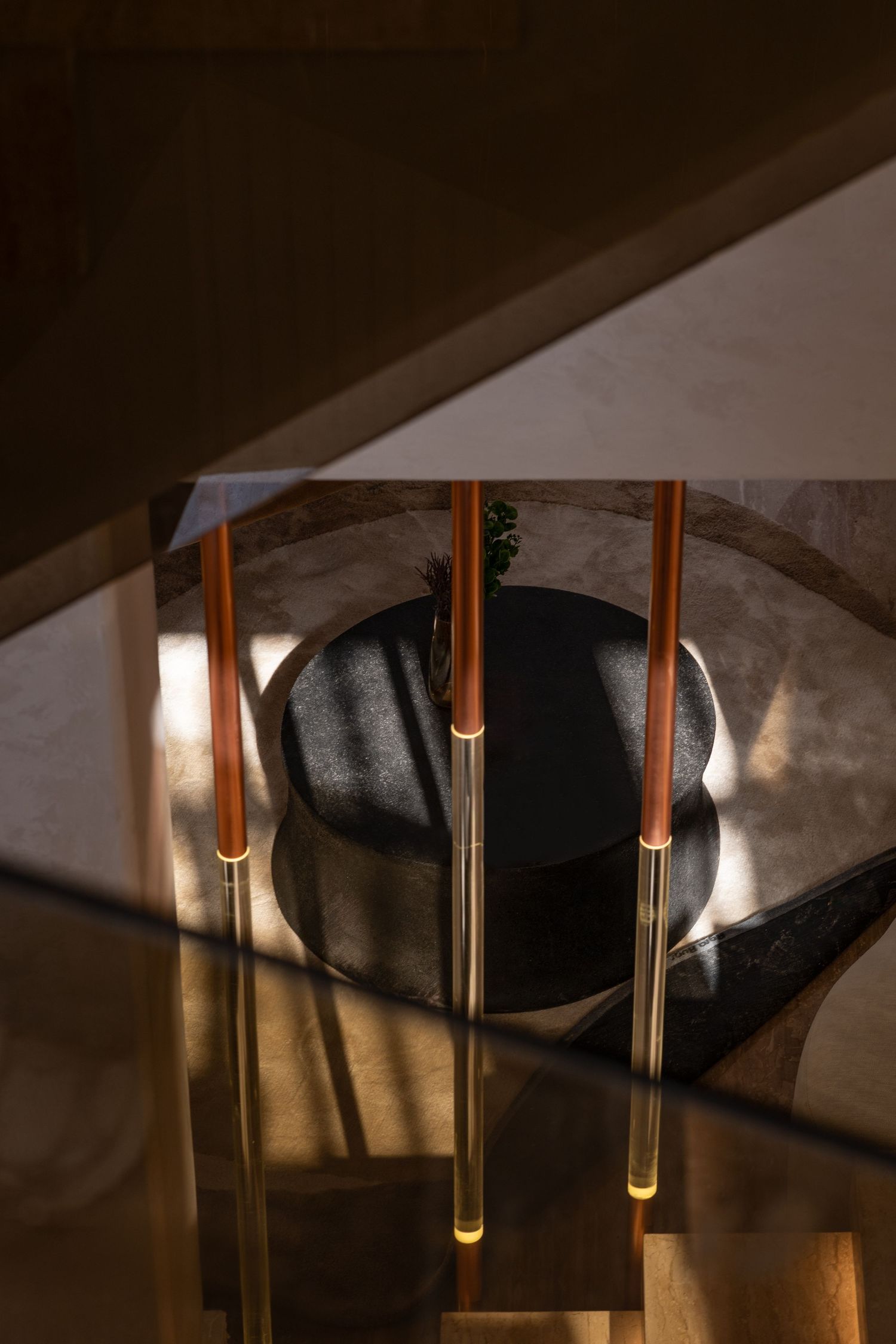 Aerial view of elegant brass and copper floor lamps surrounding a dark stone bowl on a marble floor.