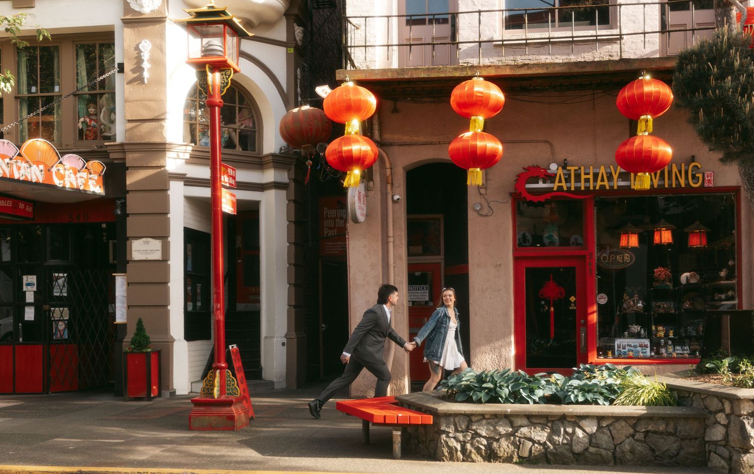 Red Chinese lanterns decorate the entrance to a storefront in Chinatown with people walking on the street.