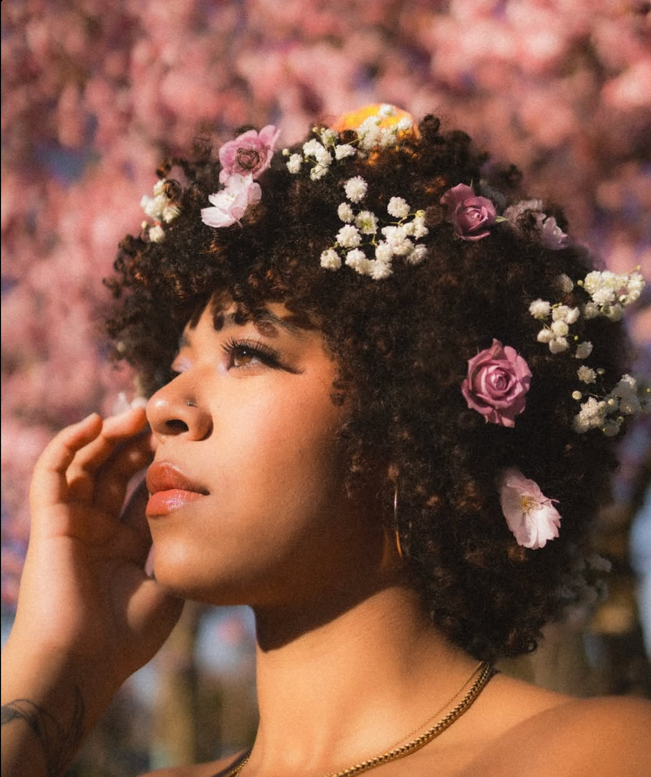 Portrait with floral crown against pink cherry blossoms creates romantic spring aesthetic.