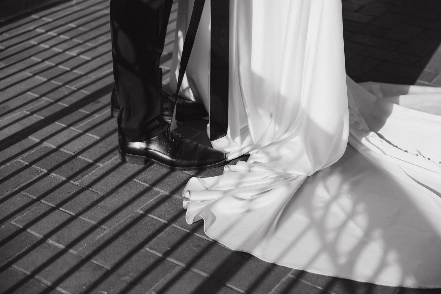 A sequence of black and white photographs showing the bottom of a wedding dress and dress shoes on wooden decking.