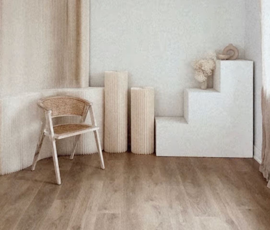 A series of minimalist wooden chairs against white walls in a gallery-like interior space.