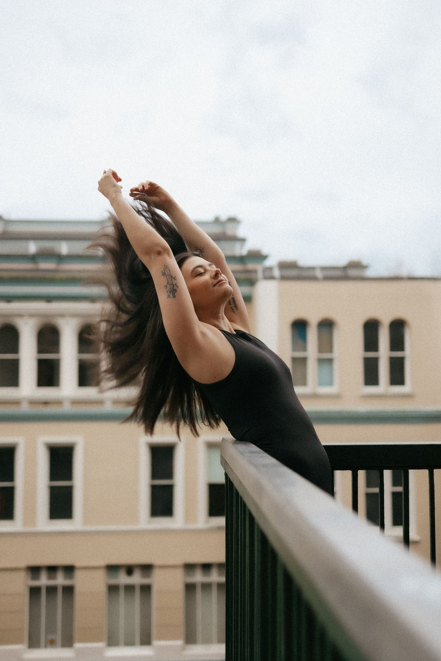 Joyful movement captured on urban rooftop with arms raised against city backdrop.