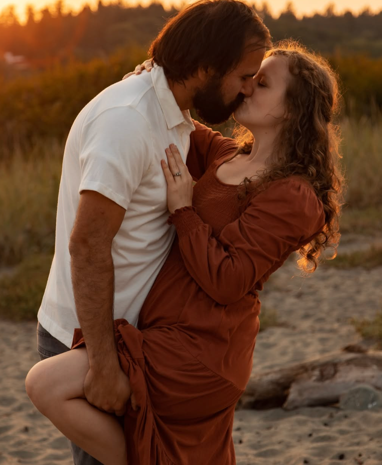 A romantic embrace between two people in a golden sunset field.