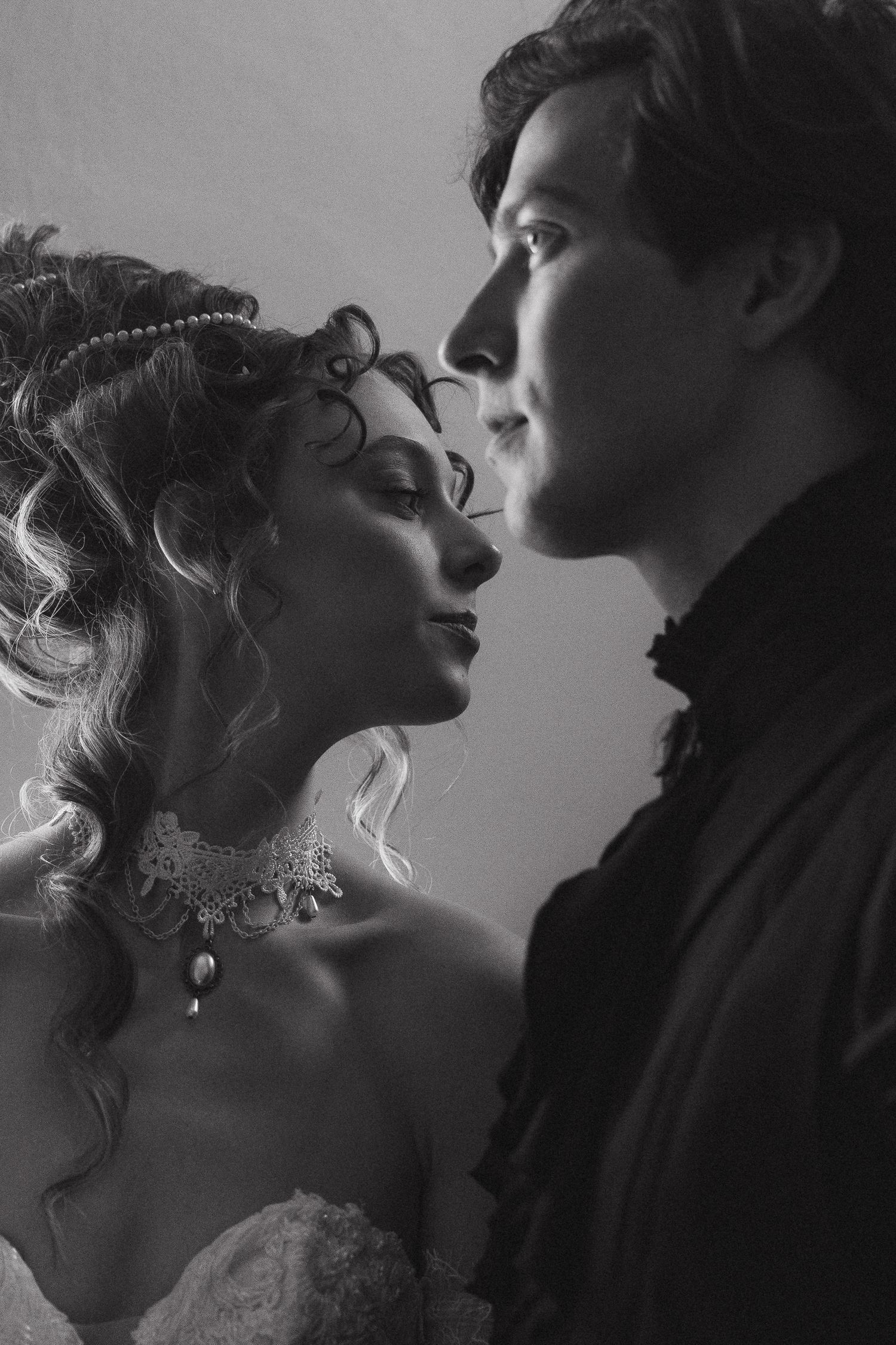 Black and white vintage portrait of an elegant couple in period attire, sharing an intimate romantic moment.