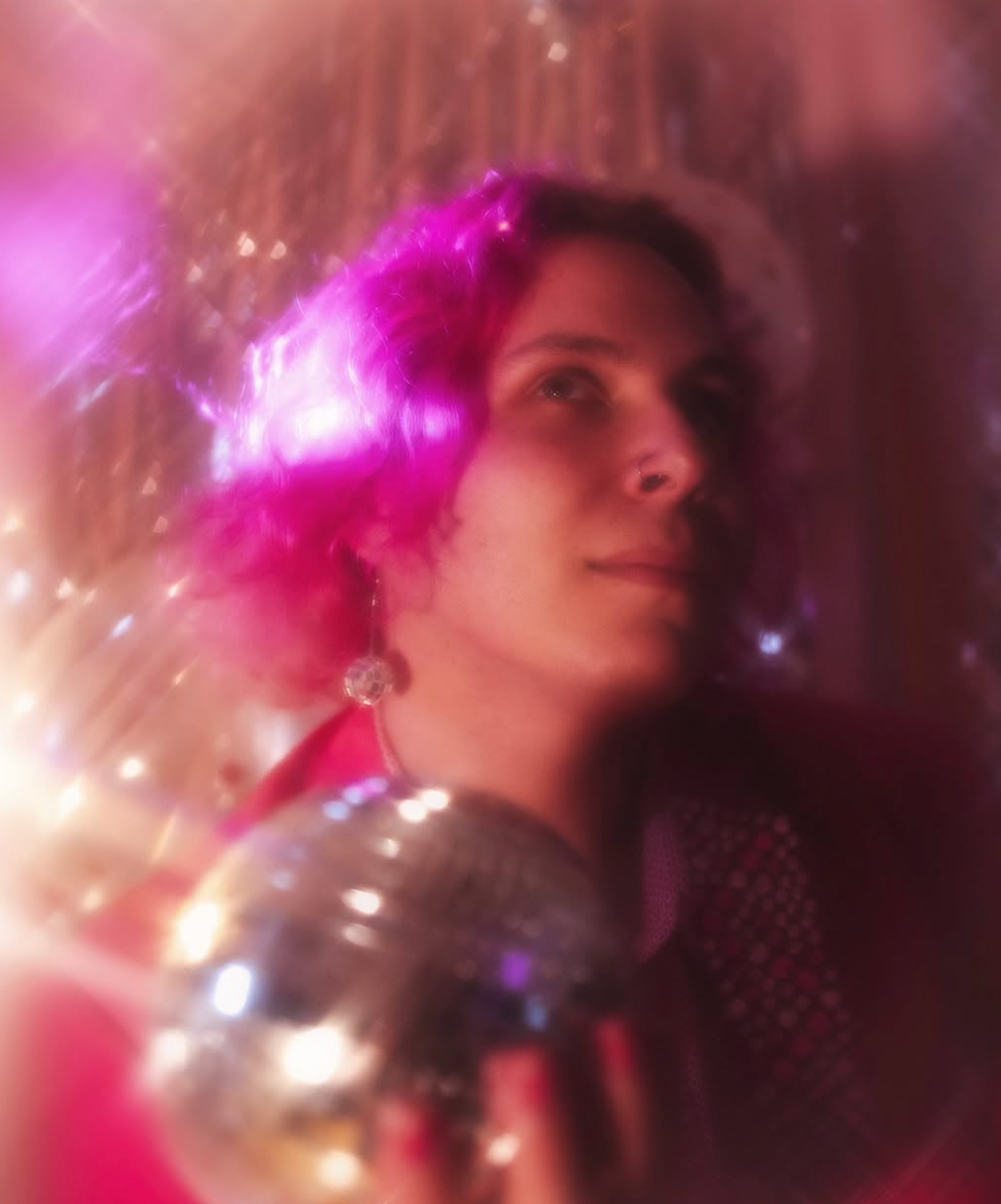 Dreamy portrait with disco ball and pink lighting creates ethereal party atmosphere.