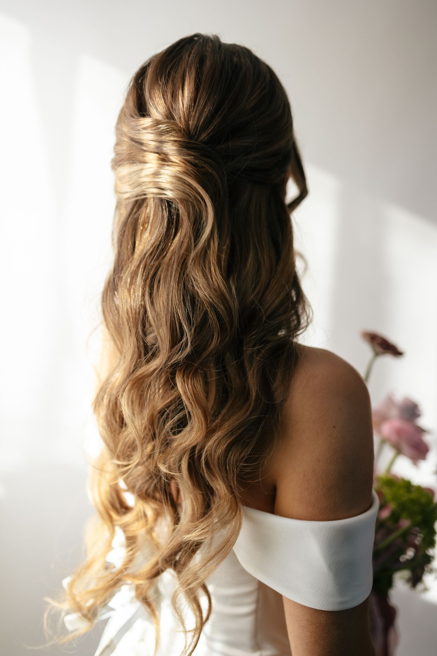 Elegant bridal hairstyle showing soft waves and braids in blonde hair styled for a wedding day.