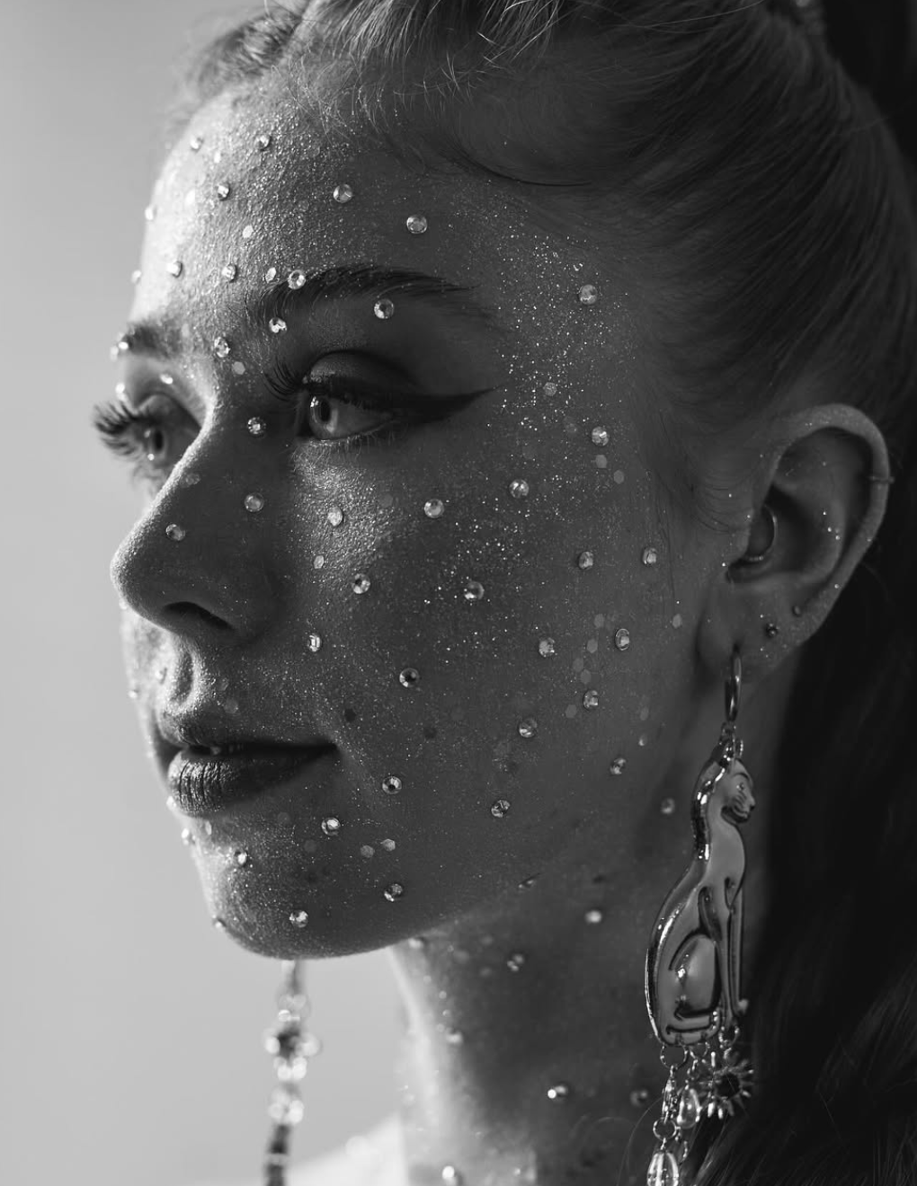 Artistic black and white portrait with water droplets and decorative earrings.