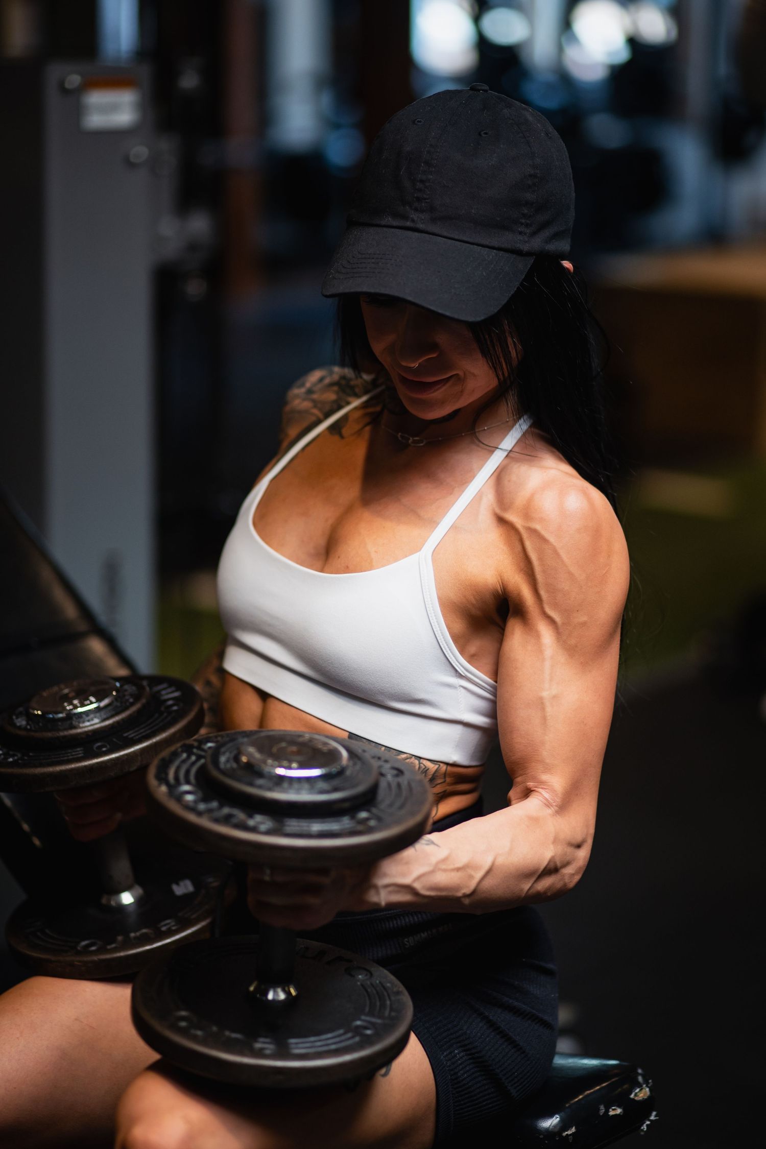 Close-up shots of muscular arms performing bicep curls with weight plates in a dimly lit gym setting.