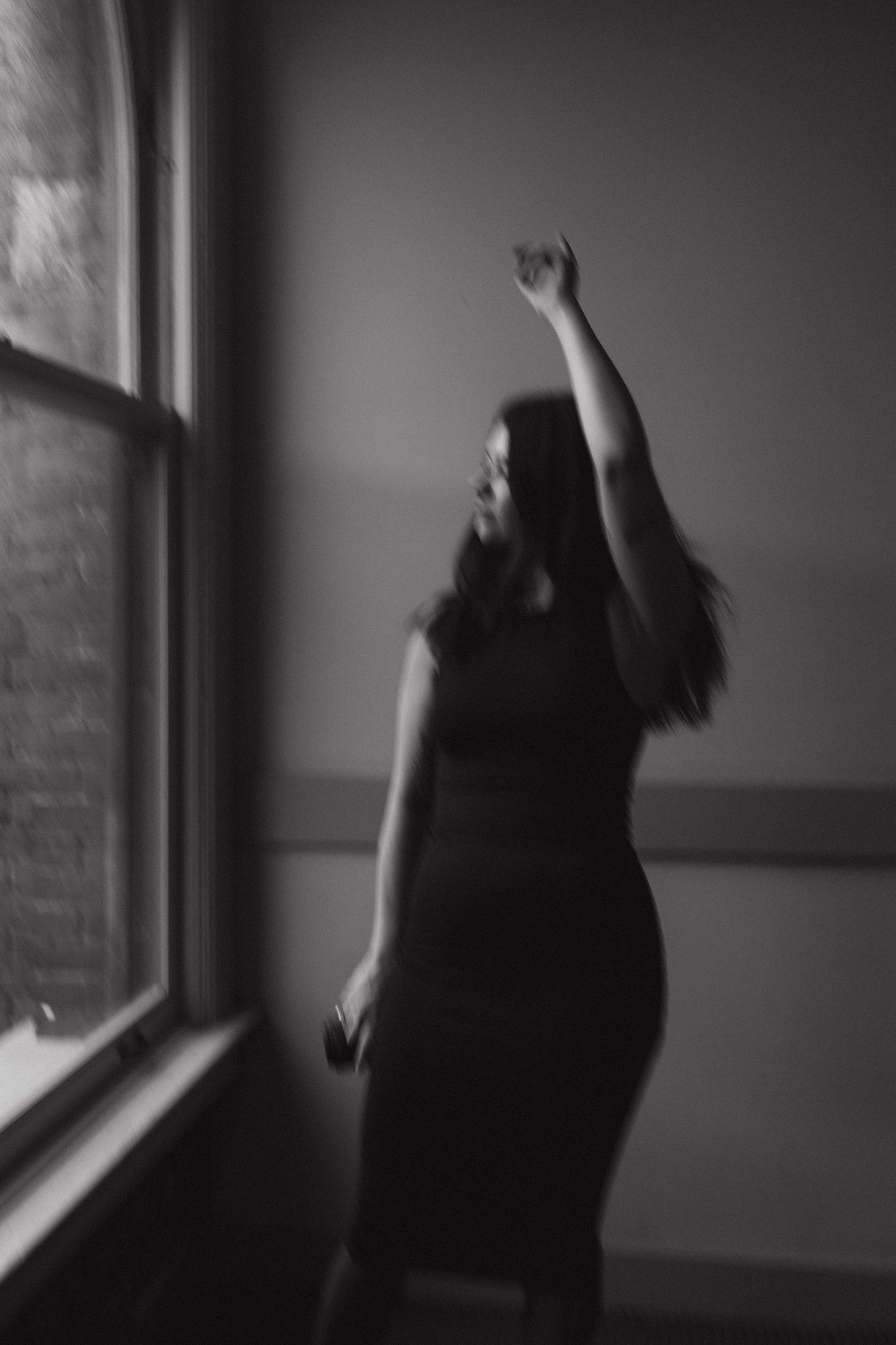 A silhouetted figure reaches up toward a window in a dark room, shown in a sequence of four moody black and white photos.