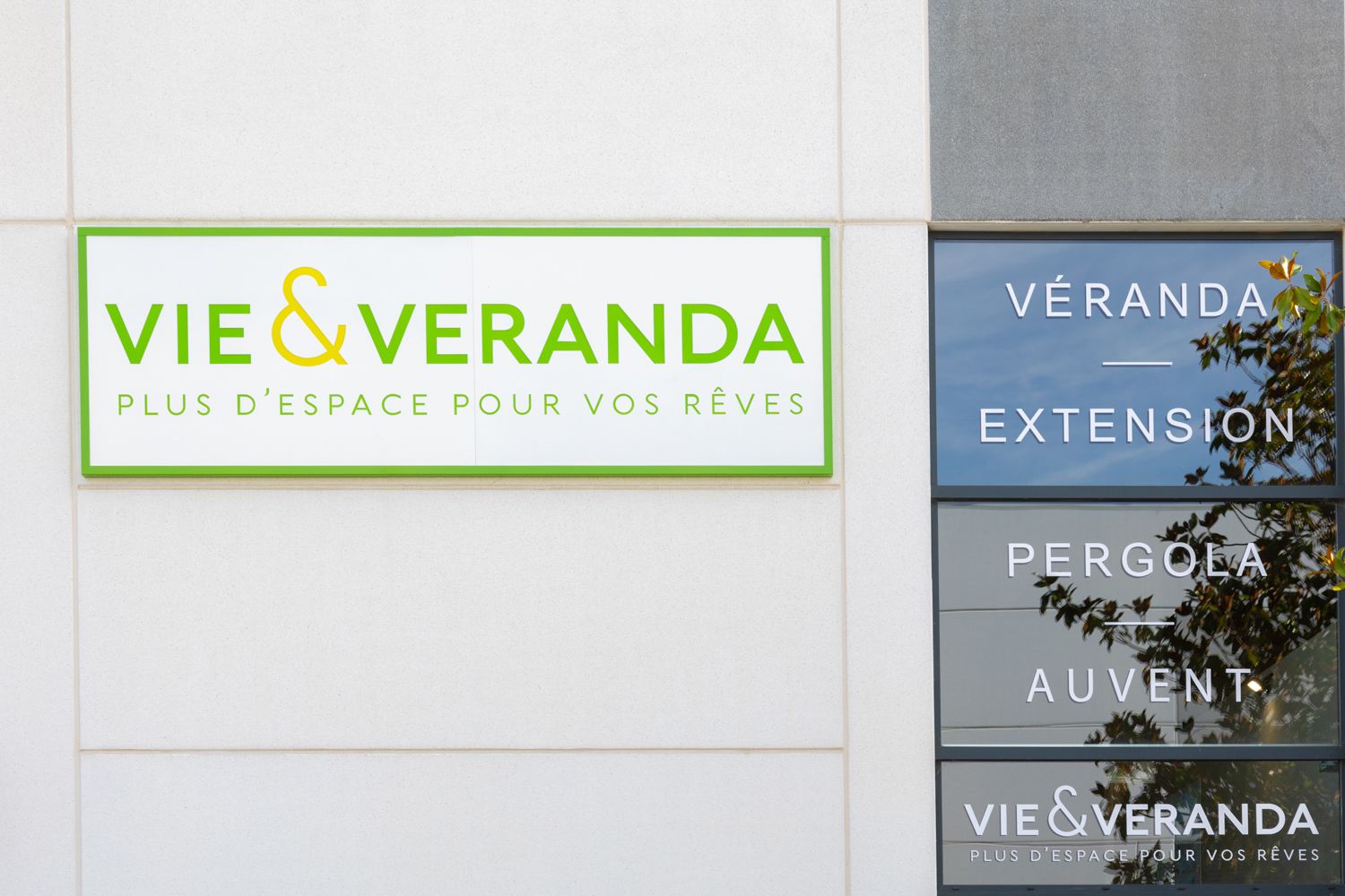 Business signage showing Vie & Veranda company logo and related service offerings on white wall.