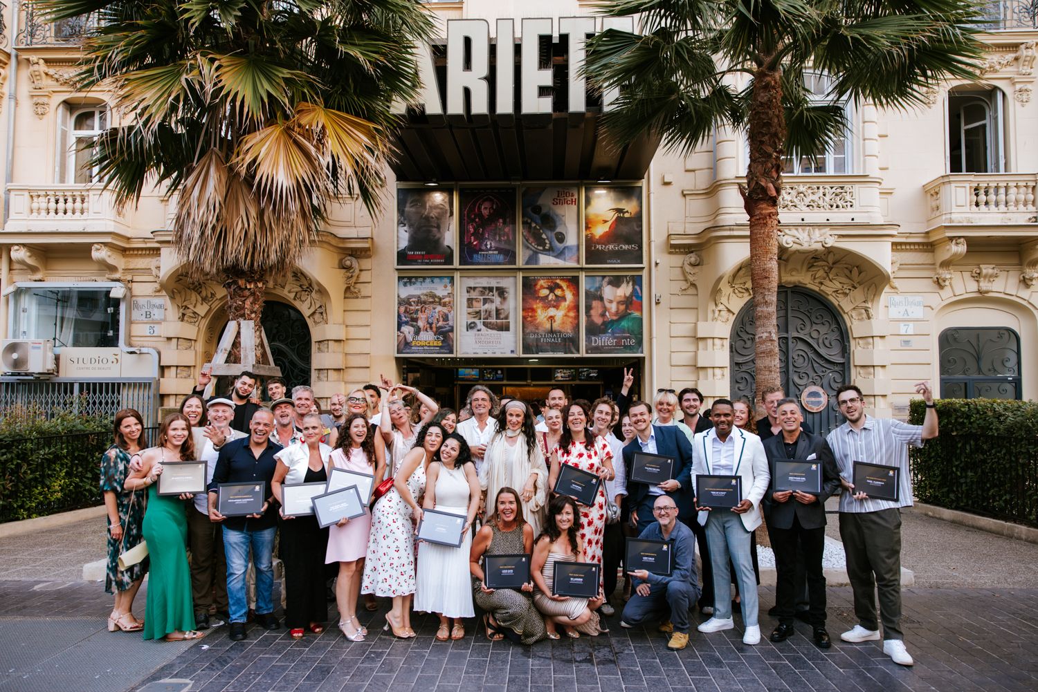 A panoramic collage of wedding guests posing together outside a historic building with palm trees.