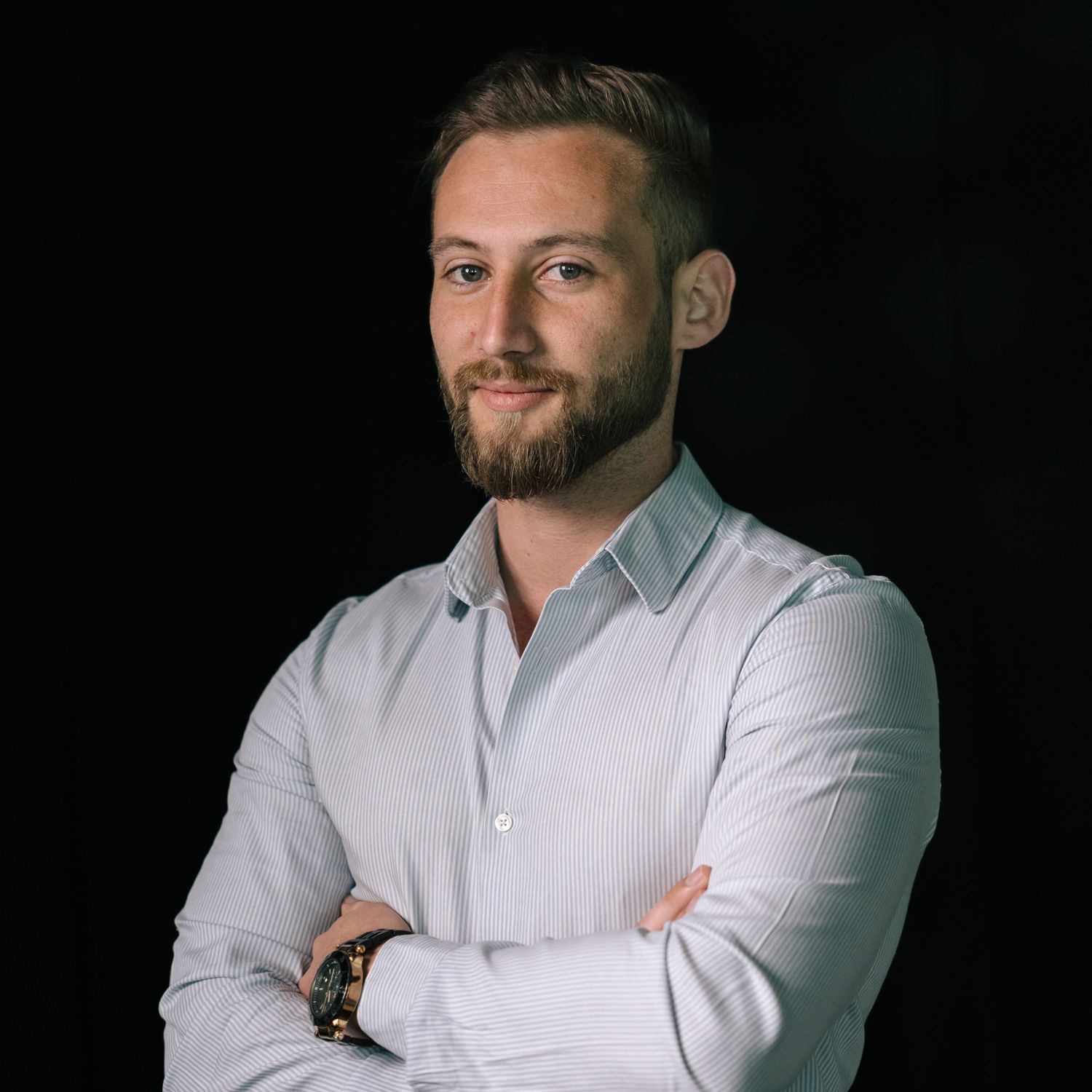 Professional headshot of someone in a light colored dress shirt against a dark background.