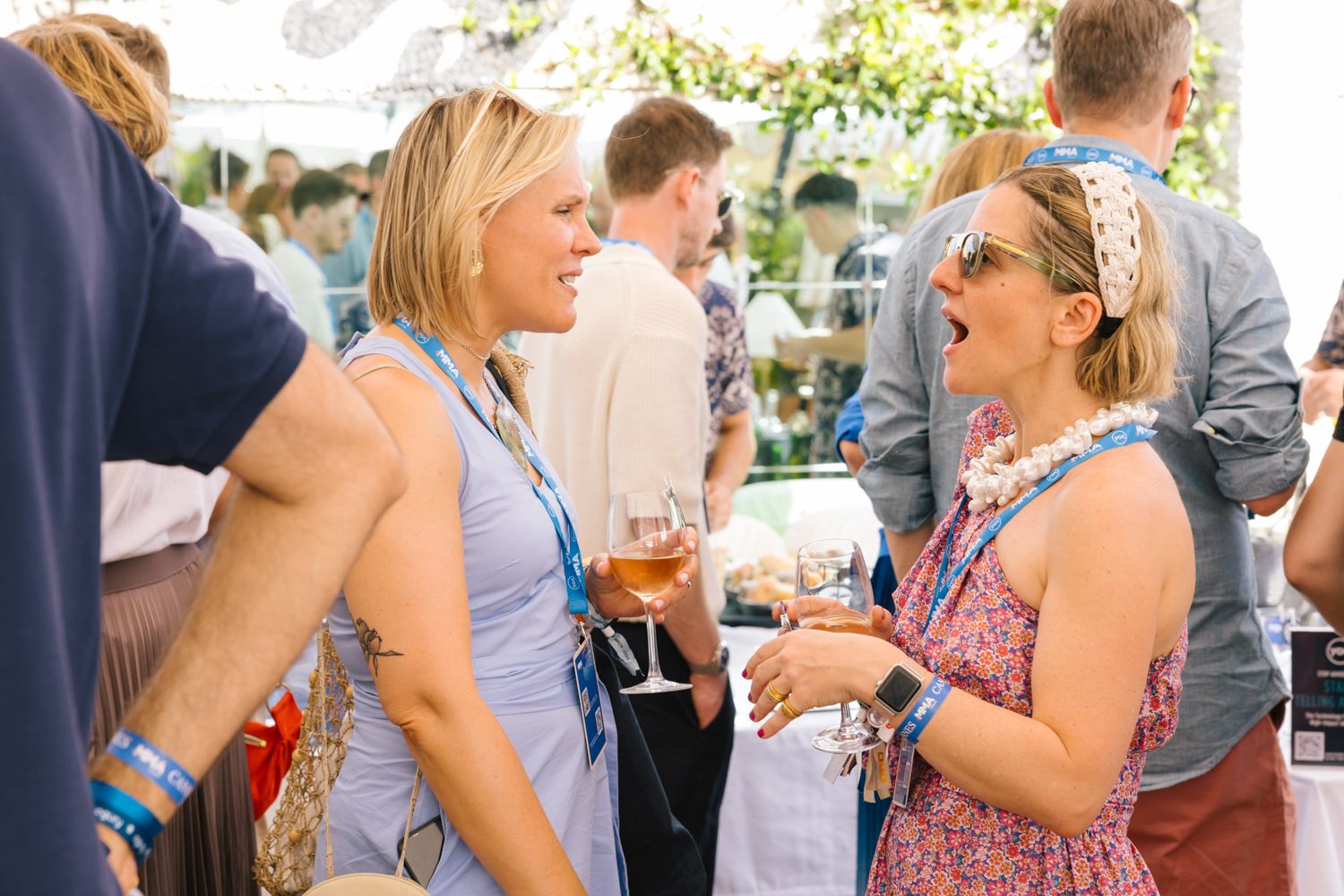 Attendees engaged in animated conversation during outdoor networking event.