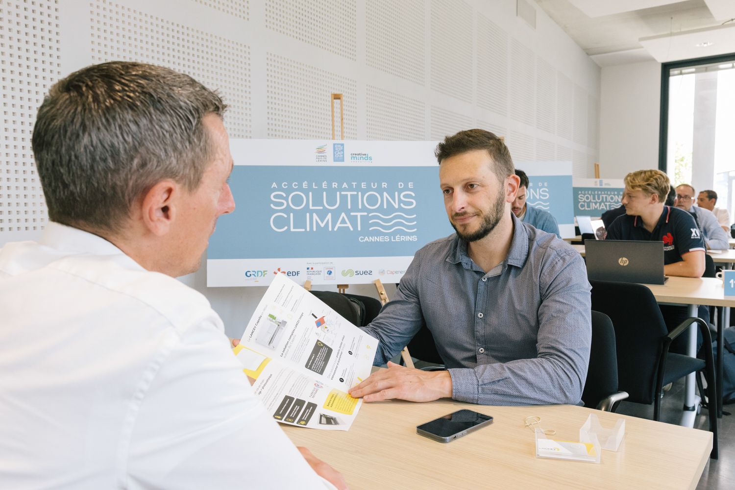 Business meeting participants discussing solutions at a table with climate signage.