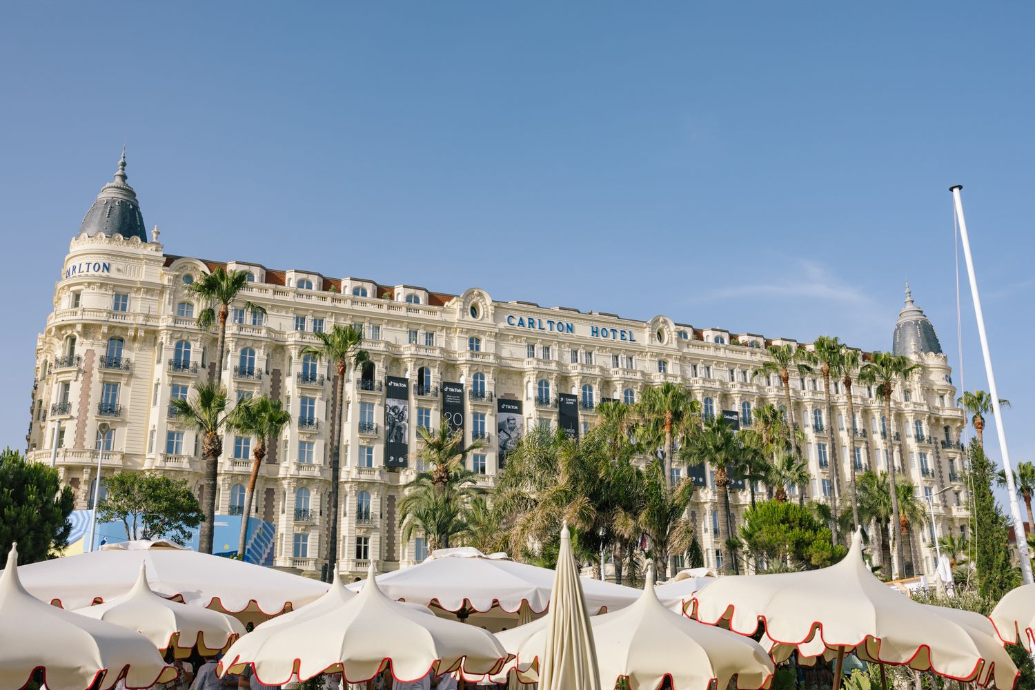 Luxurious Carlton Hotel in Cannes with classic French architecture and beachfront umbrellas.