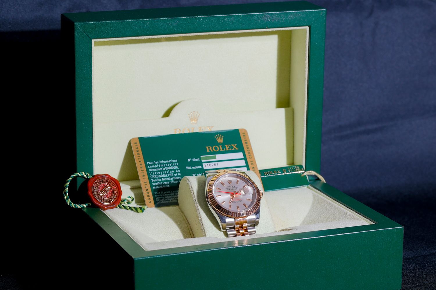 Luxury watch displayed in an elegant green presentation box with certificate and documentation.