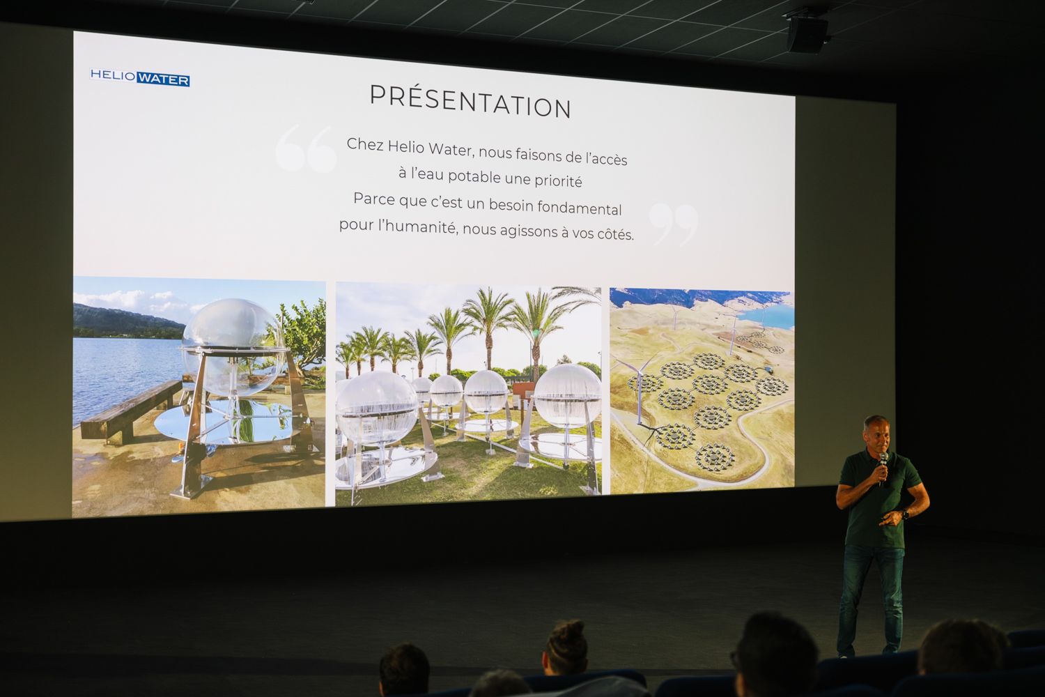 Presenter discusses solutions with landscape images displayed on large screen during conference.
