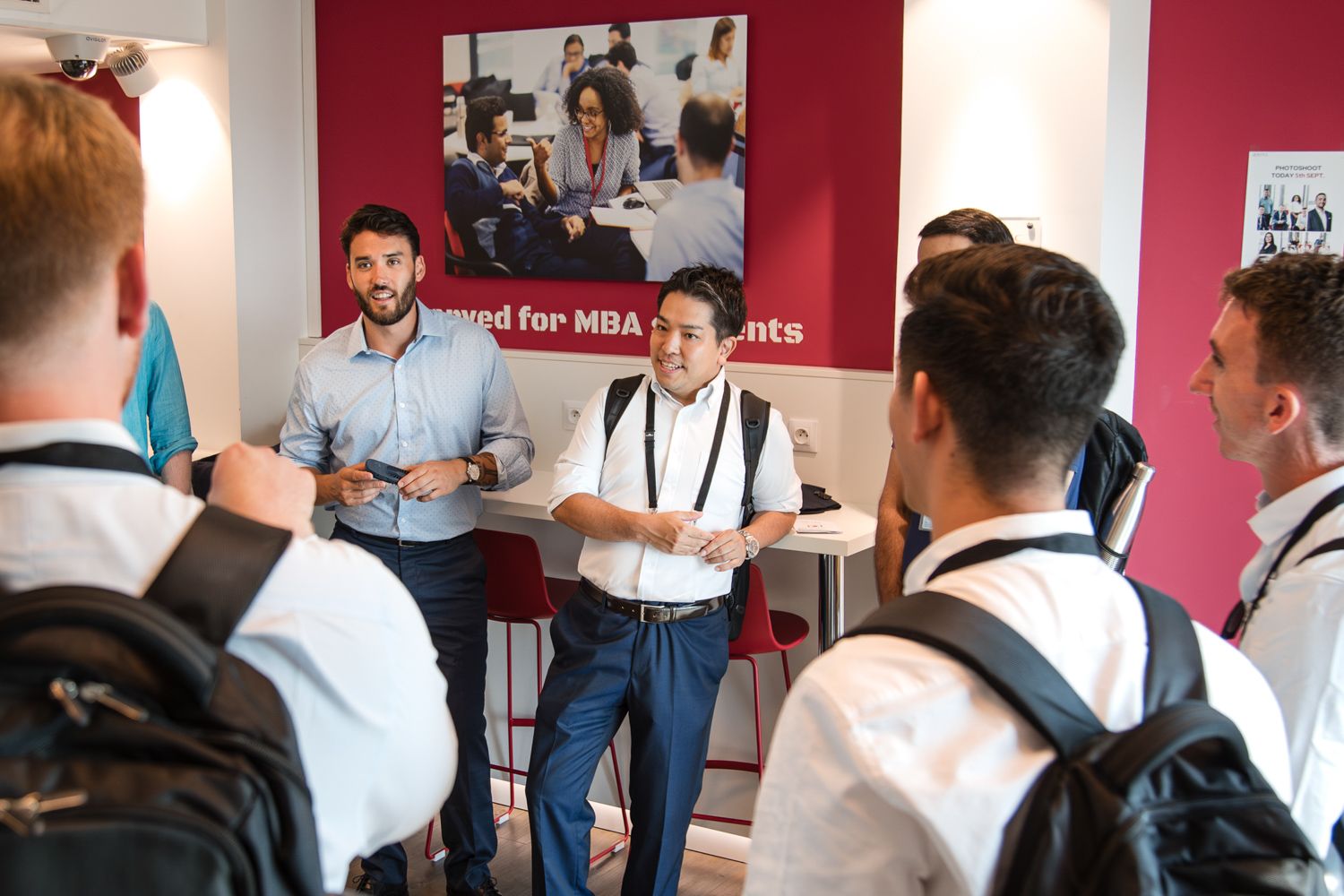 Students gathered in a hallway with red walls during an educational session.