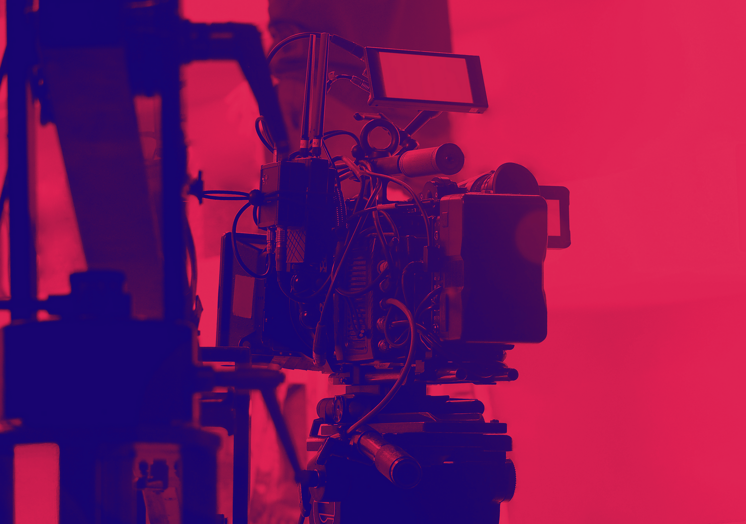 Professional video camera silhouetted against a red background.