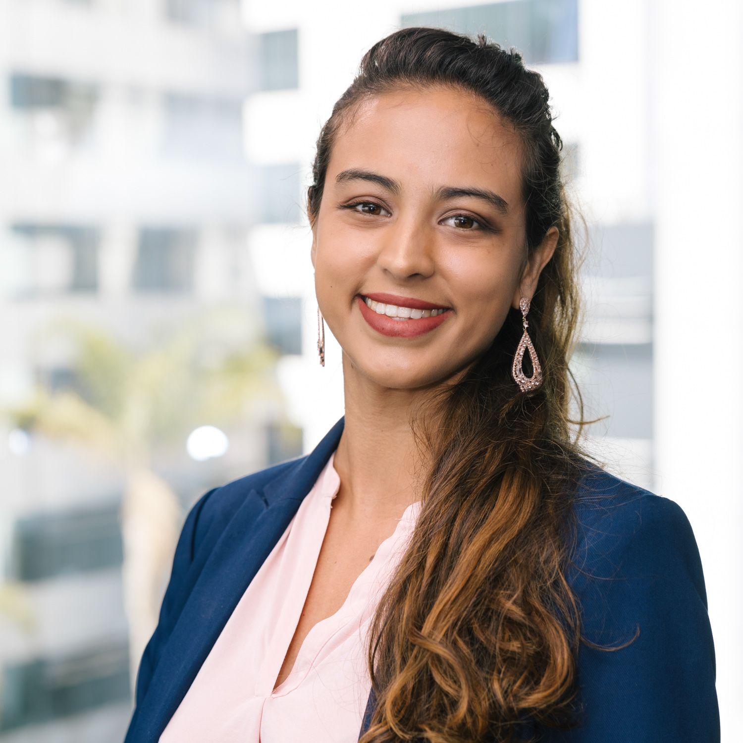 Professional in navy blazer and pink blouse in modern office setting.