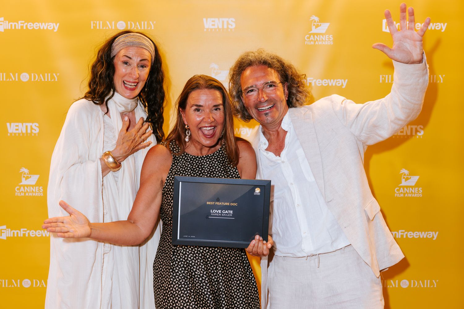 A group of people celebrating and posing with laptops against a bright yellow backdrop.