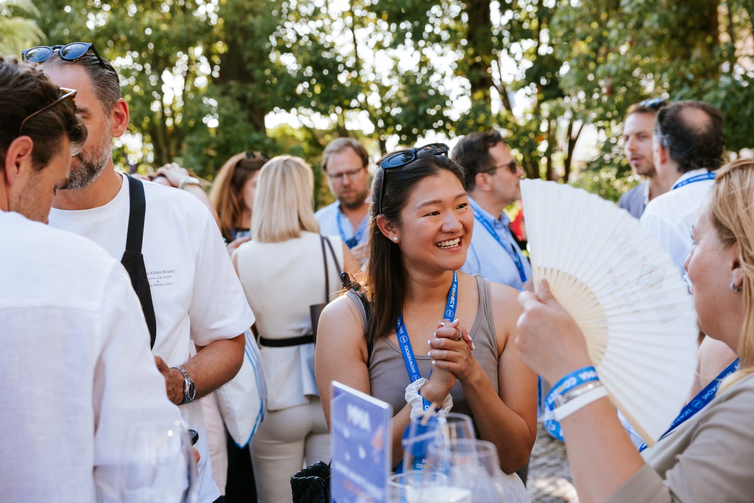 Wedding guests mingle and socialize during an outdoor reception in a garden setting.