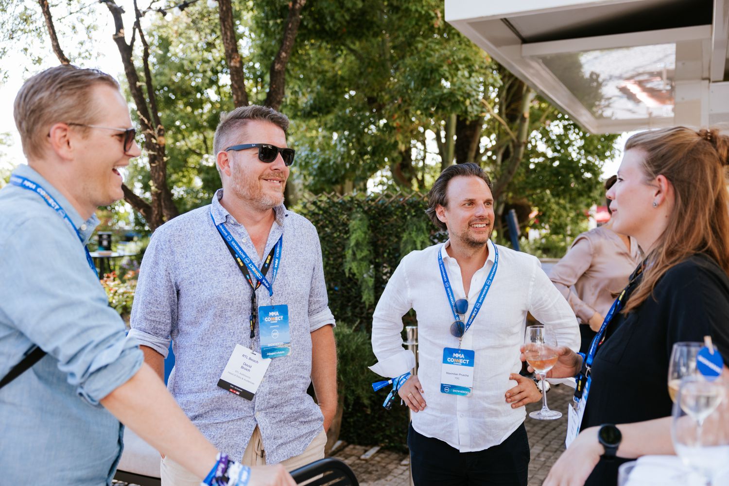 Group of people in business casual attire engaged in animated conversation at an outdoor networking event.
