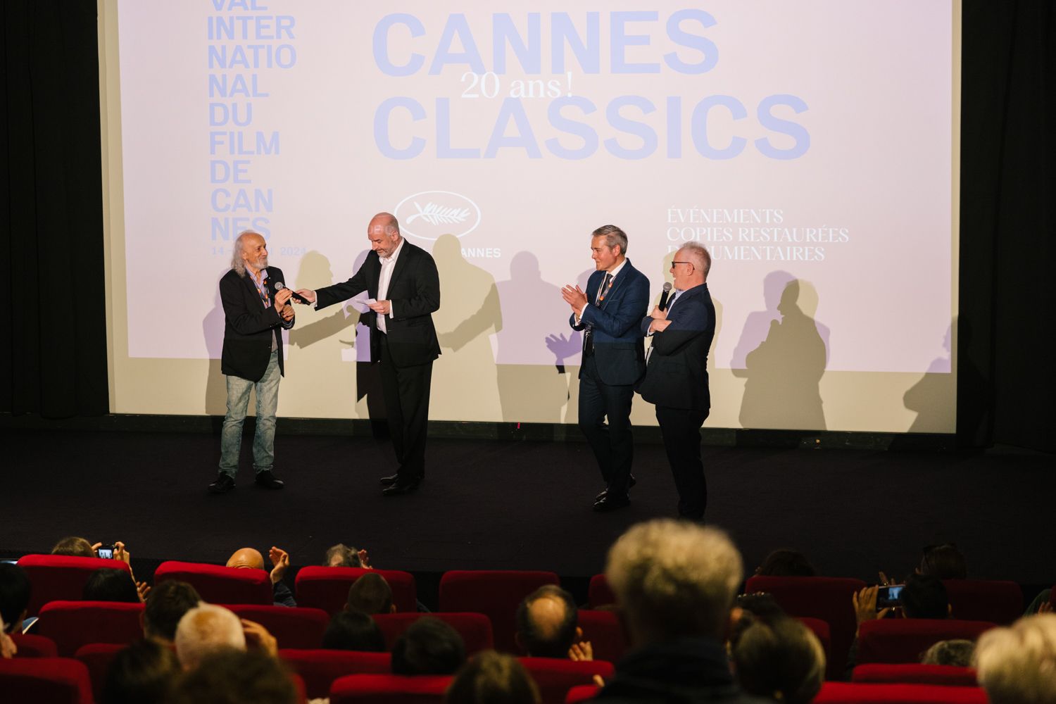 People on stage during a Cannes Classics presentation in a movie theater.