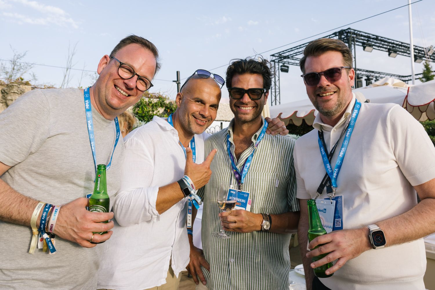 Group of conference attendees enjoying drinks and conversation in casual attire outdoors.