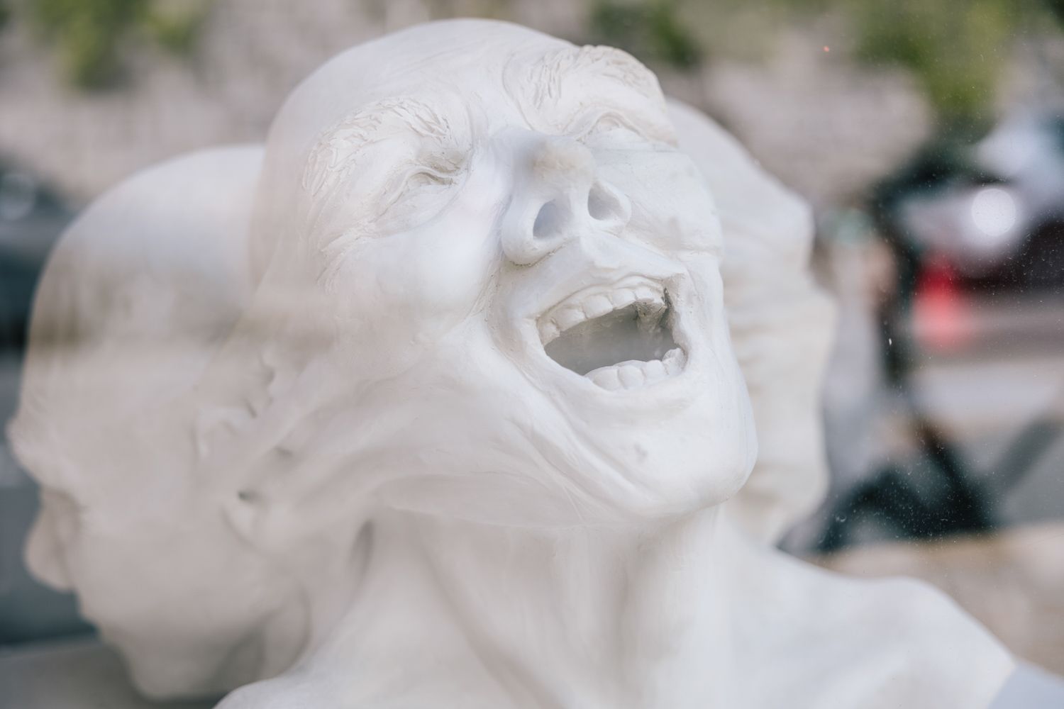 Close-up of expressive white sculpture showing laughter and emotion.
