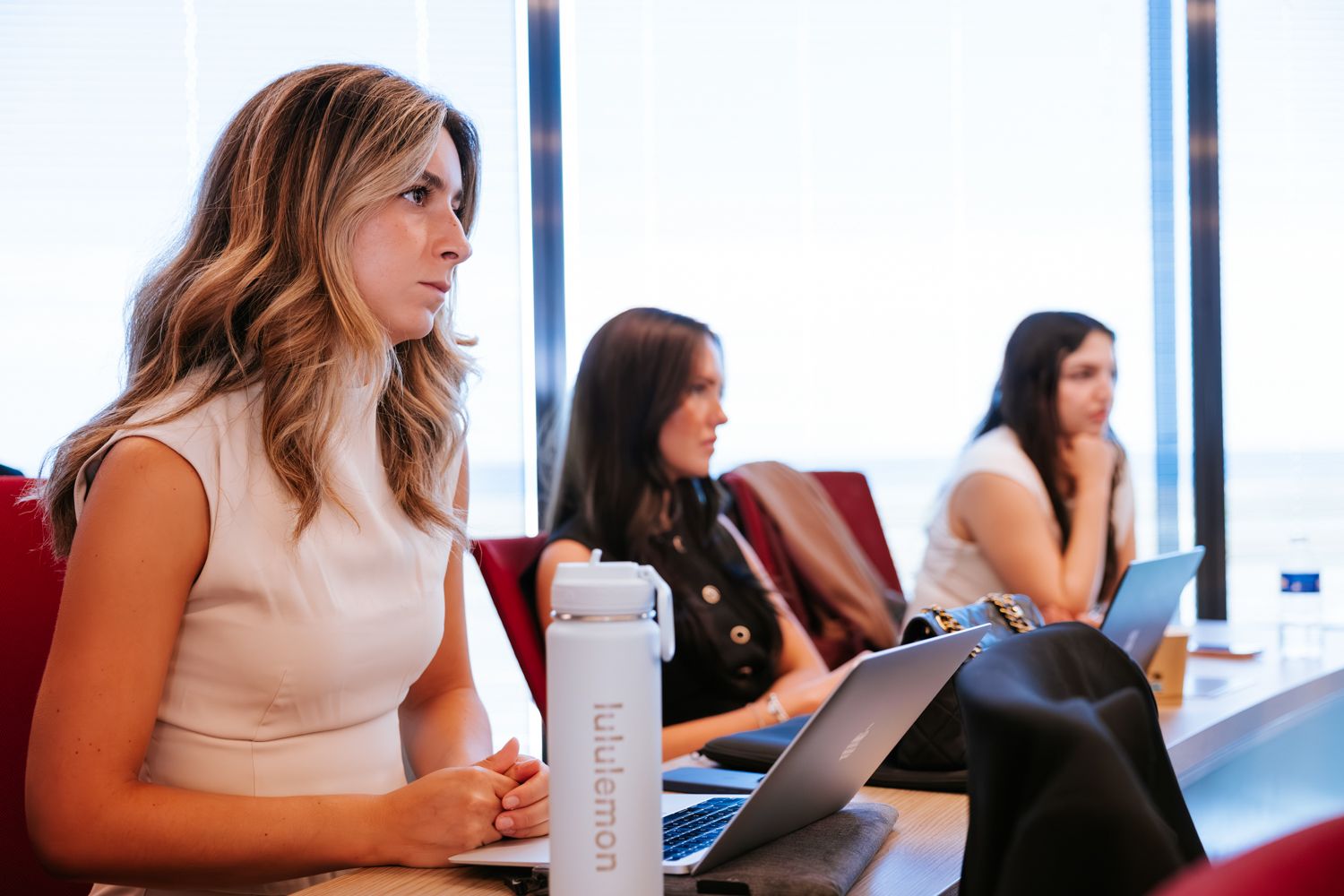 People sitting at a conference table during a business meeting in a modern office with large windows.