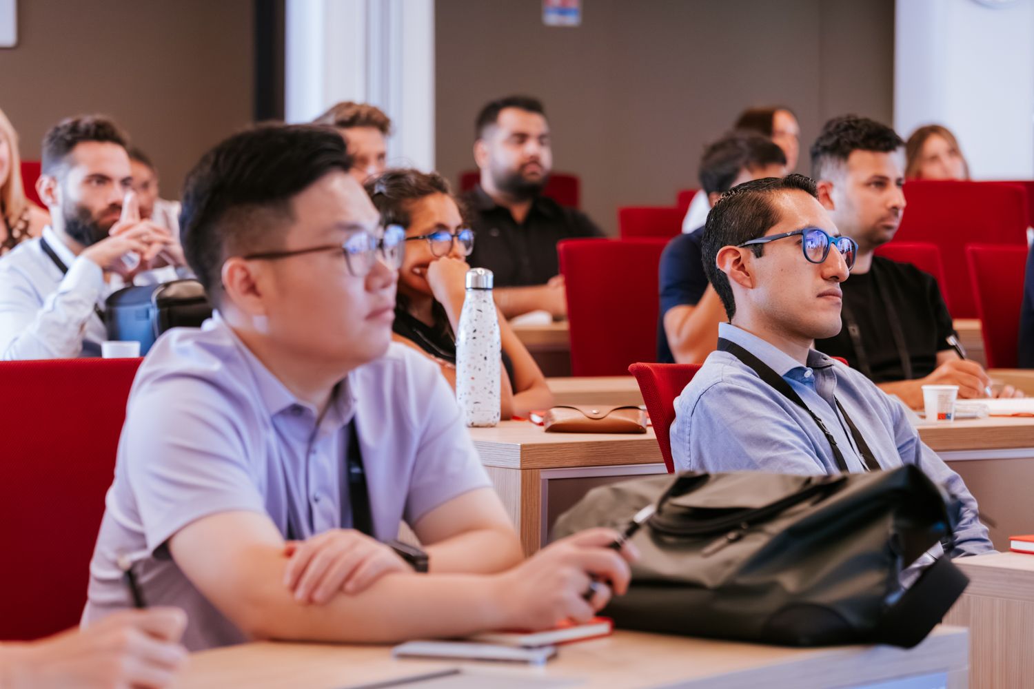 Students sitting at desks in a classroom listen attentively during a lecture or presentation.