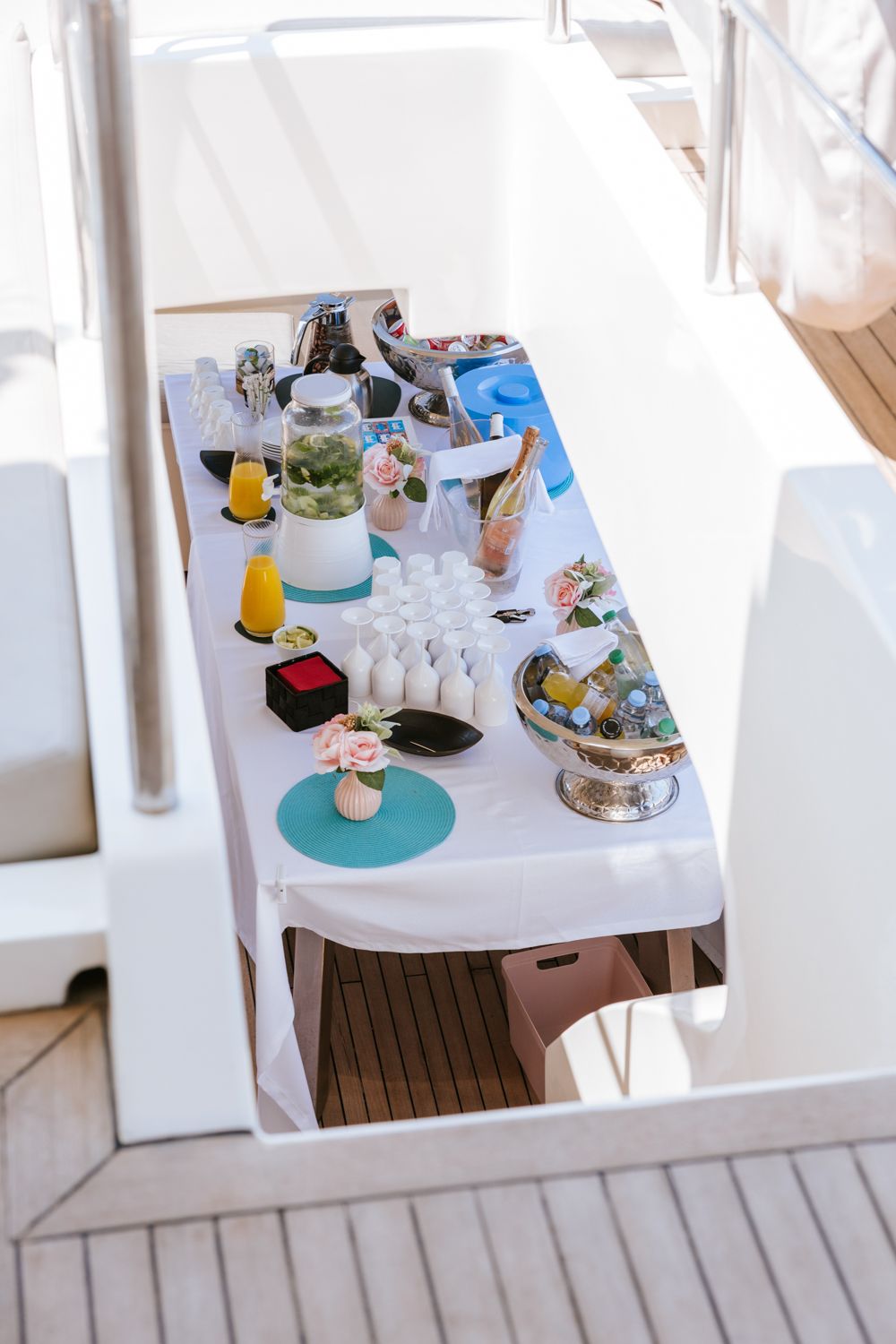 White tables set with turquoise placemats and refreshments on a bright outdoor patio or deck area.