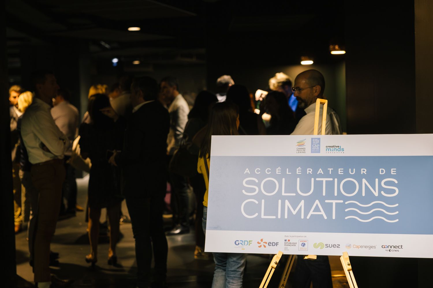 Conference networking event with climate solutions banner displayed on easel stand.