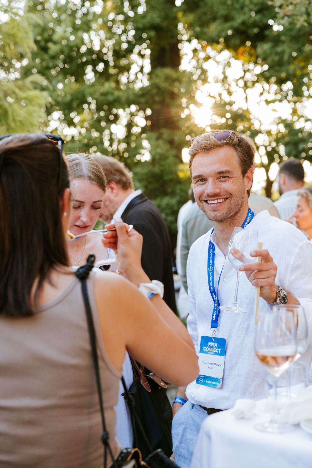 People enjoying wine and conversation at an outdoor social gathering during golden hour.