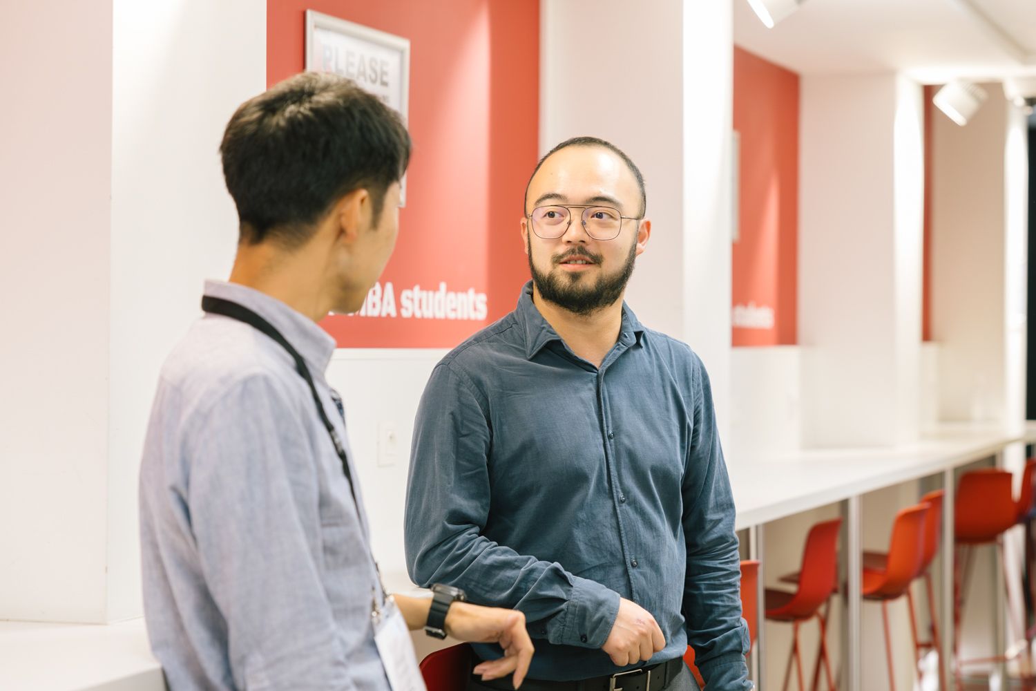 Two professionals having a conversation in modern office hallway.