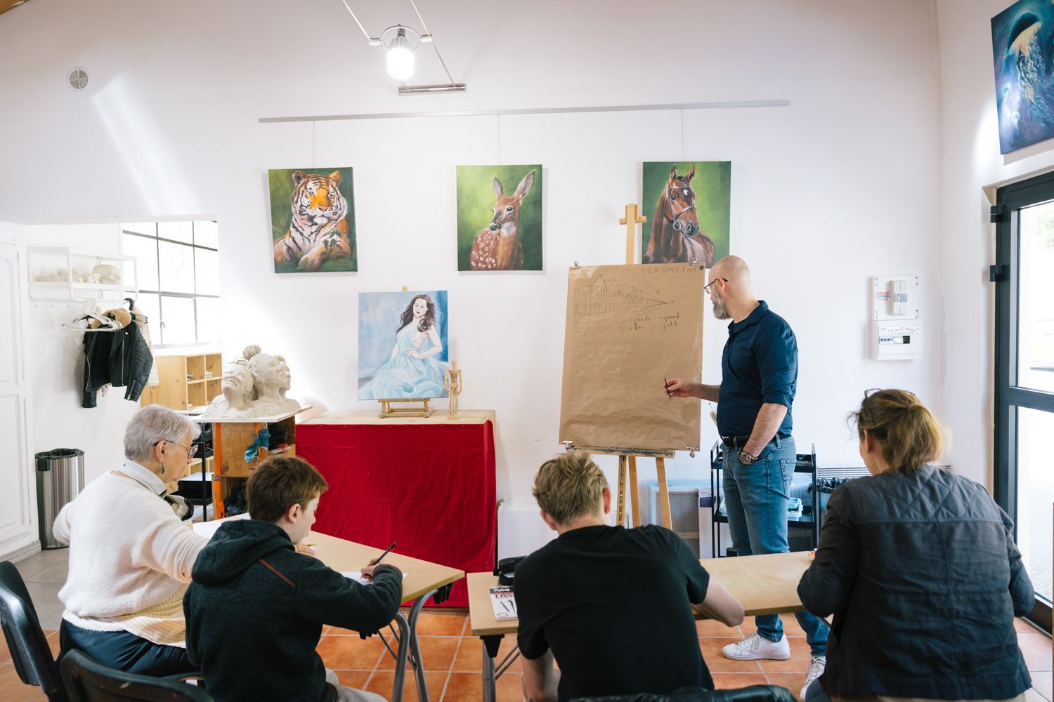 Students attend an art workshop while an instructor presents sketches on brown paper.