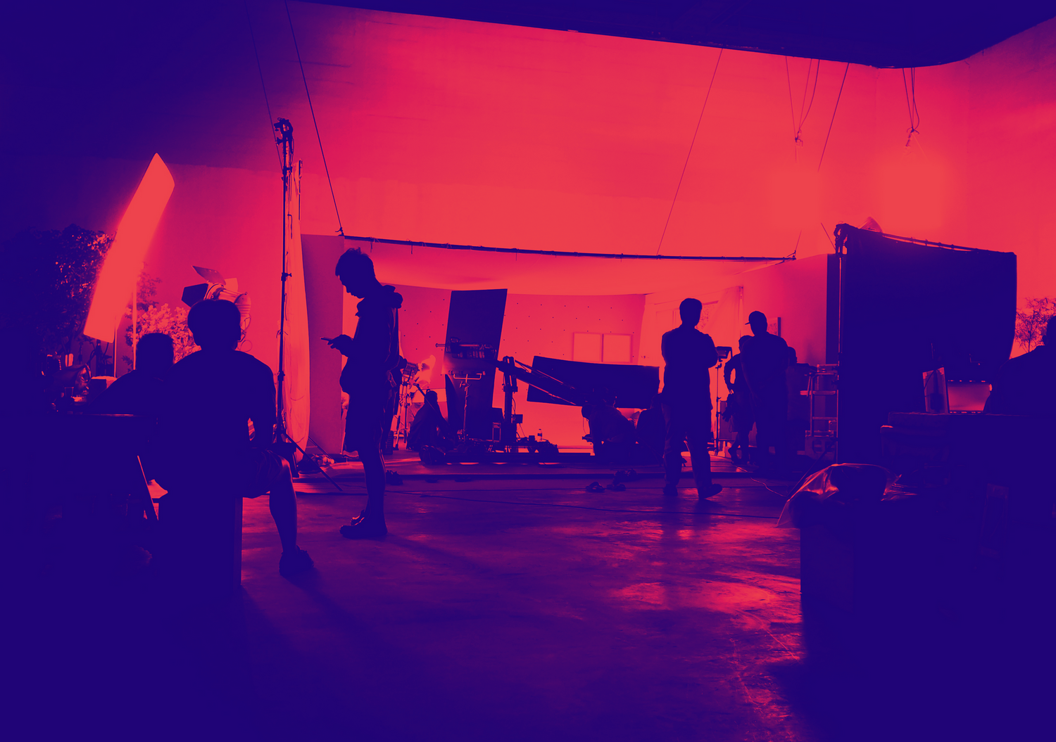 Film crew silhouettes working on movie set with dramatic red lighting.